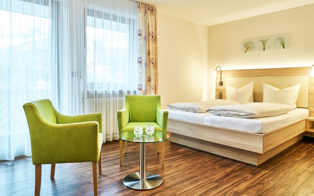 a hotel room with a bed and two green chairs at Fewo Heiligenberg - Waßmer in Heiligenberg