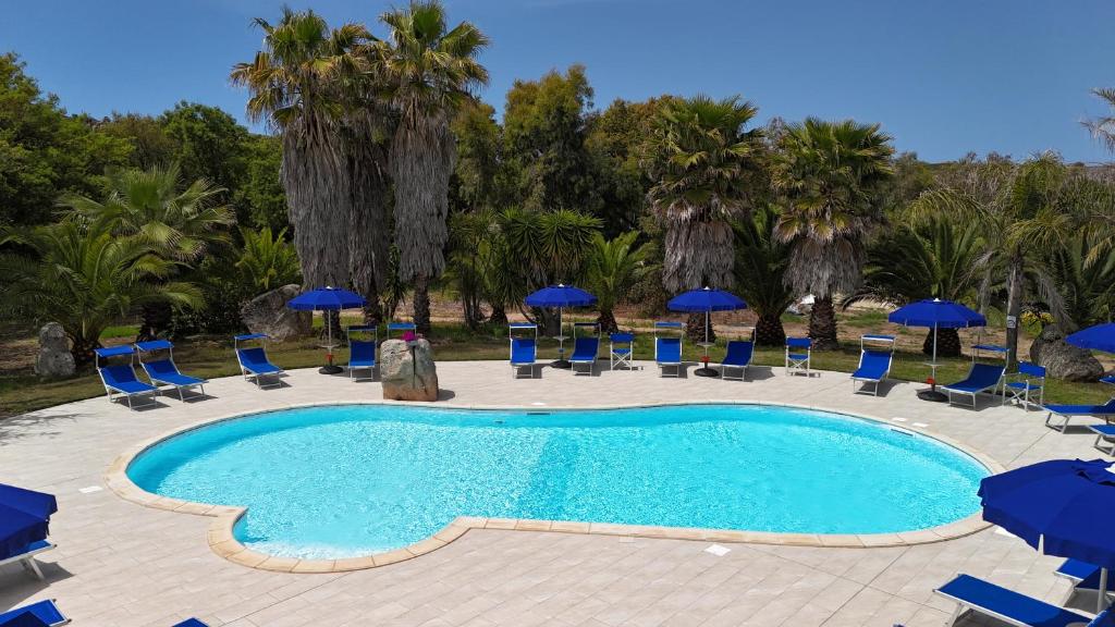 a swimming pool with chairs and blue umbrellas at Agriturismo Rocce Bianche in Arbus