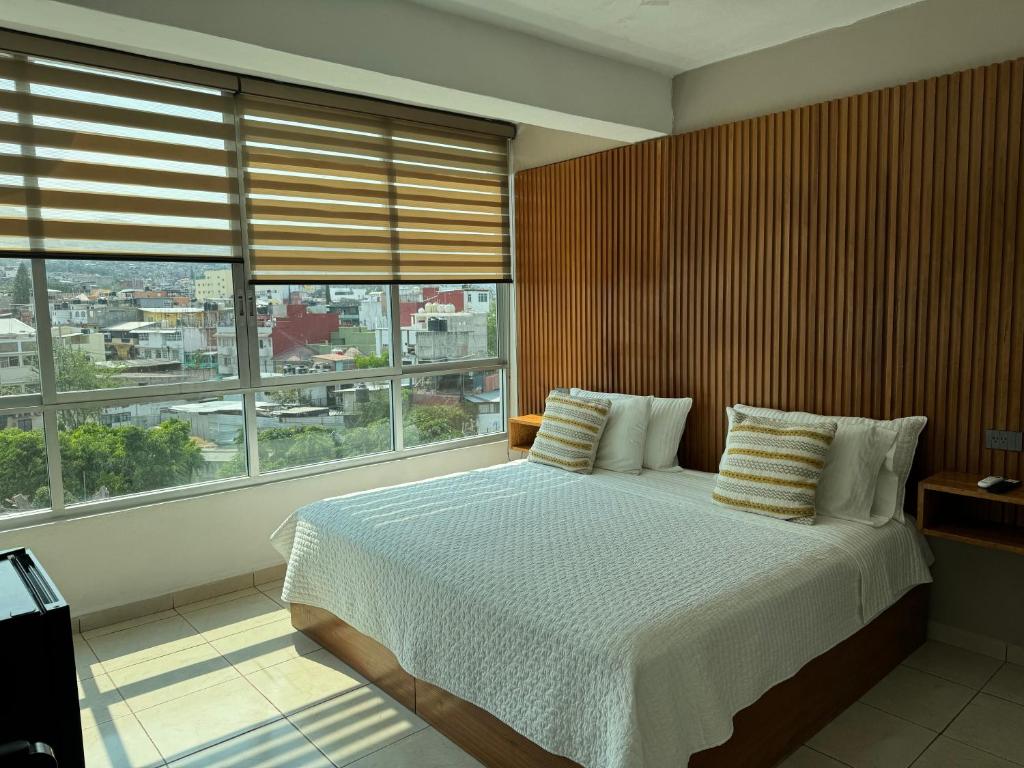 a bedroom with a large bed with a large window at Hotel Daba Suites in Chilpancingo de los Bravos