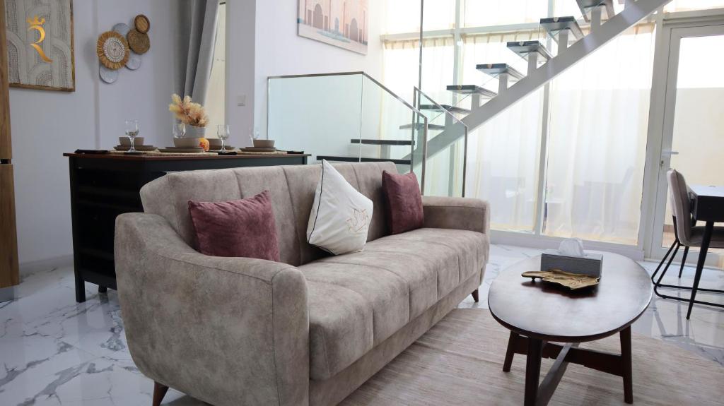 a living room with a couch and a table at Aurora Your 2BR Duplex Transit Apartment in Abu Dhabi