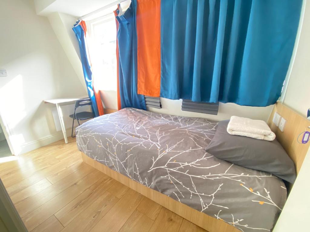 a bedroom with a bed with blue and orange curtains at Not Very Quiet But Best location in London