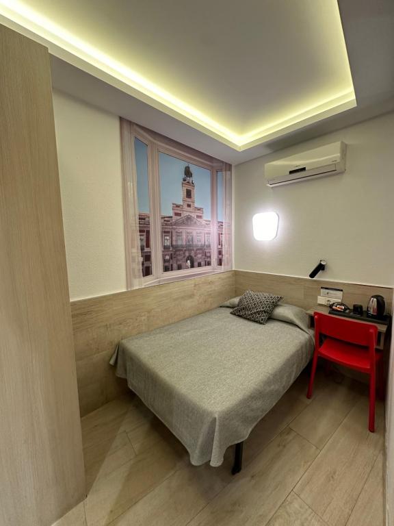 a bedroom with a bed and a window and a red table at Hostal Castilla II Puerta del Sol in Madrid