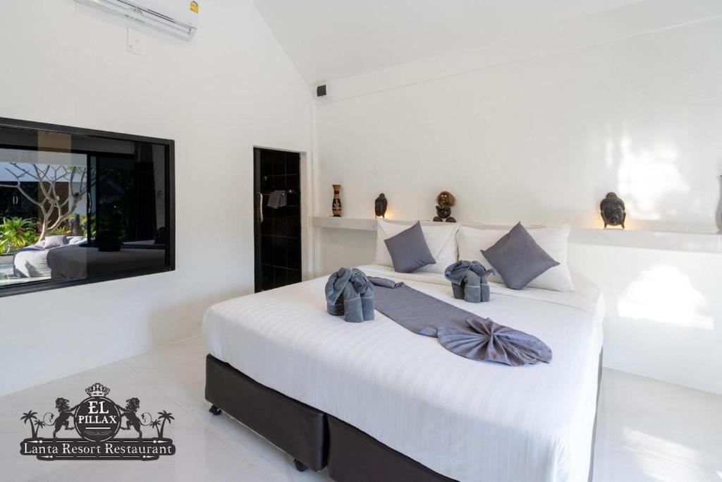 1 dormitorio con 1 cama con sábanas blancas y TV en Stunning Bungallow in El Pillax Lanta resort en Phra Ae beach