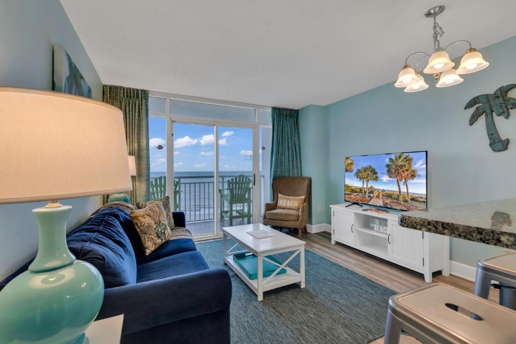 a living room with a blue couch and a view of the ocean at Ocean Front 2BR Elegant Condo in Atlantica Resort in Myrtle Beach
