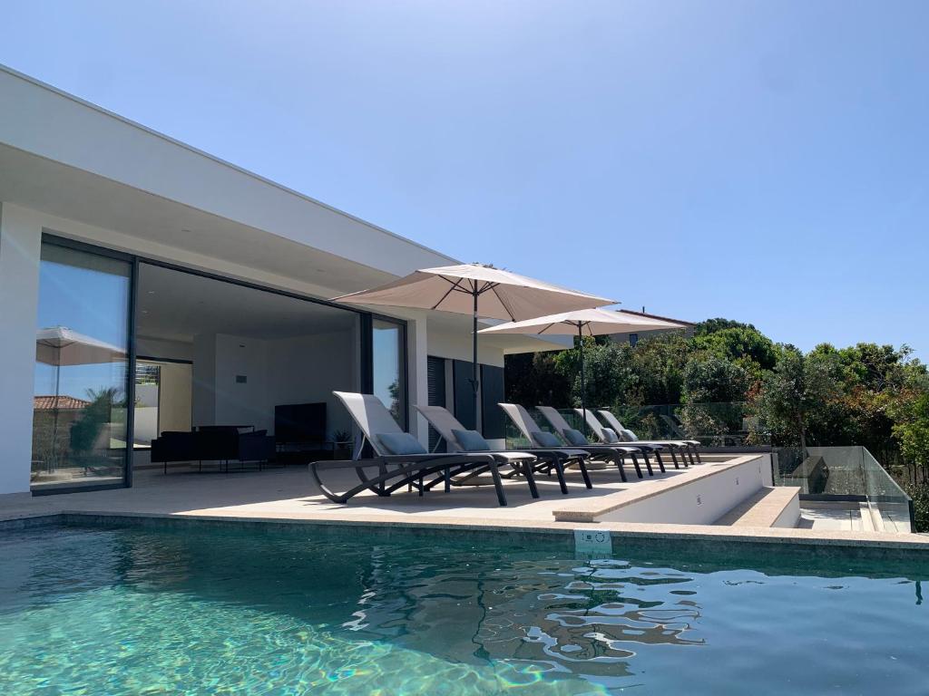 a pool with chairs and umbrellas next to a house at VILLA IMPERIALE vue mer piscine in Pietrosella