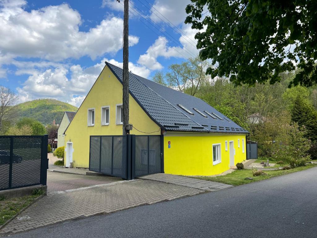 żółty dom z czarnym dachem na ulicy w obiekcie Penzion V Podzámčí w mieście Moravská Třebová
