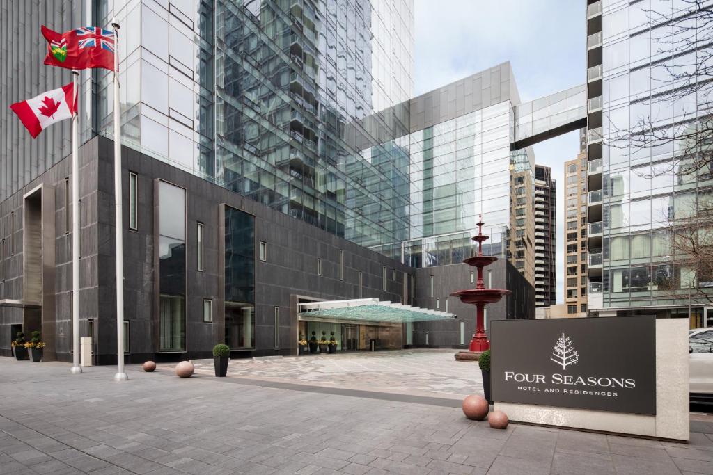 ein hohes Glasgebäude mit einem Schild davor in der Unterkunft Four Seasons Hotel Toronto at Yorkville in Toronto