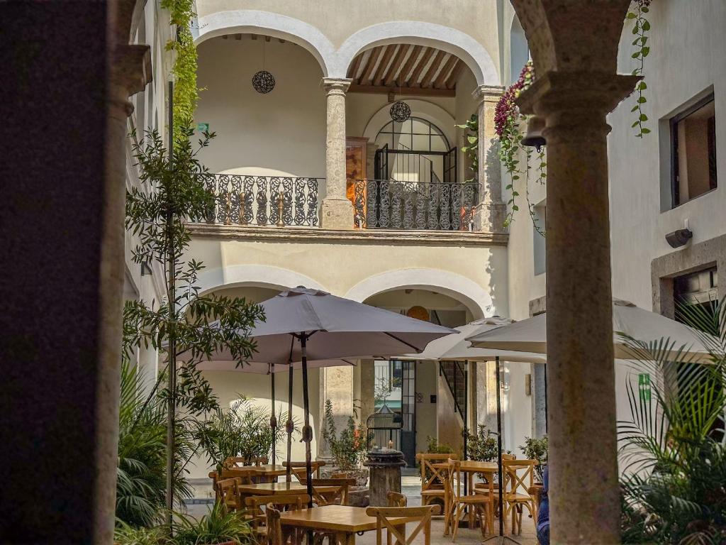 un patio con mesas y sombrillas en un edificio en Palpatio Hotel en Guadalajara