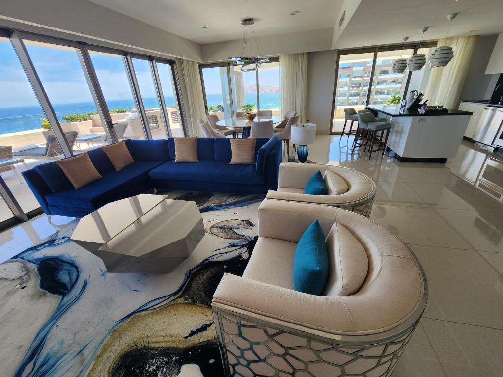 a living room with couches and chairs and the ocean at Garza Blanca Los Cabos in Cabo San Lucas