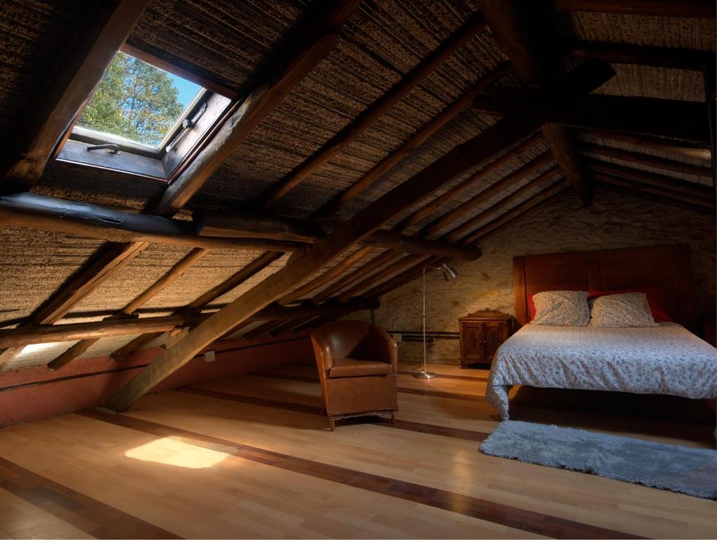 1 dormitorio en el ático con 1 cama y 1 silla en El Sumiciu, en Mieres
