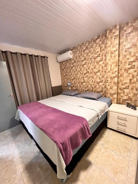 a bedroom with a bed and a brick wall at Casa espaçosa e aconchegante Jphouse in São José