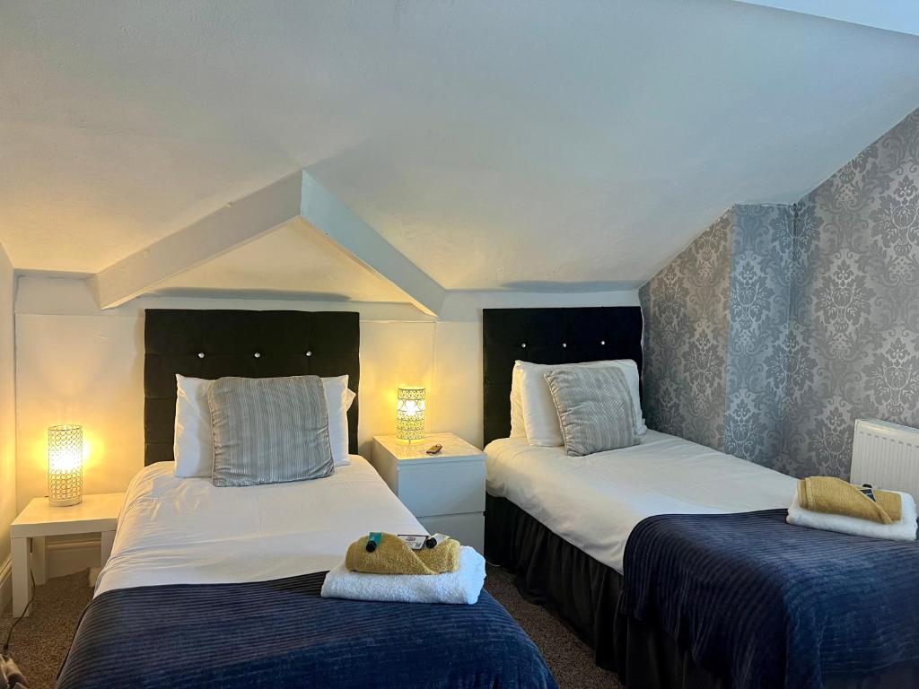 a bedroom with two beds with blue sheets and two lamps at St Andrews house Hotel in Preston