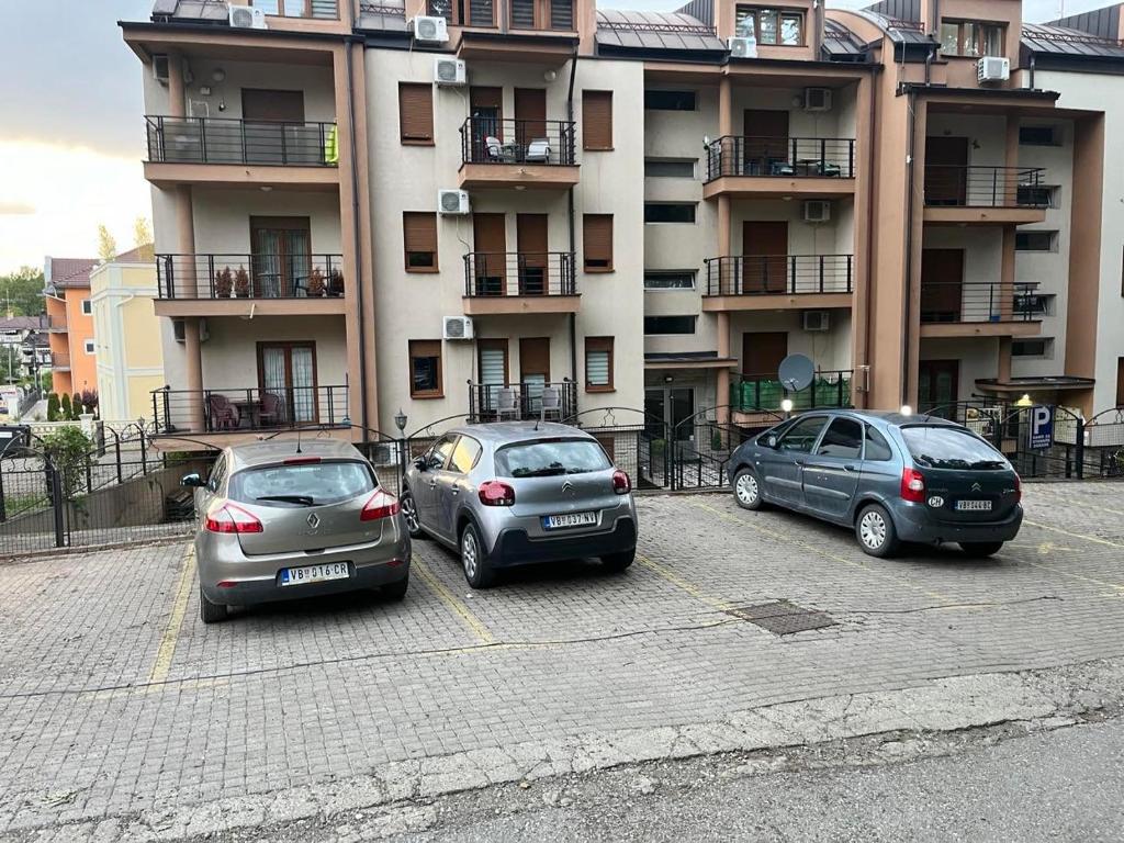 drei Autos auf einem Parkplatz vor einem Gebäude geparkt in der Unterkunft Studio Verica in Vrnjačka Banja