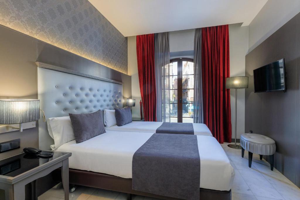 a bedroom with a large white bed and red curtains at Hotel Ciutadella Barcelona in Barcelona