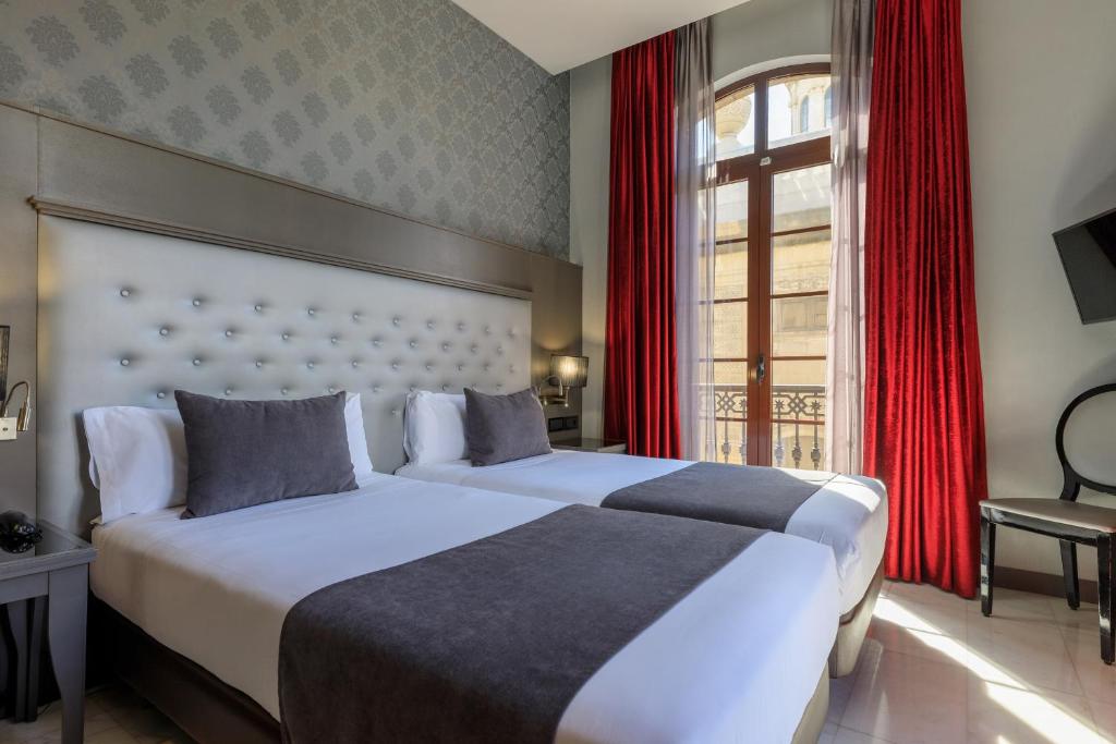 two beds in a hotel room with red curtains at Hotel Ciutadella Barcelona in Barcelona