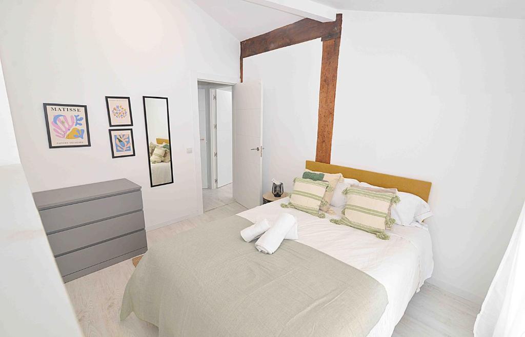 - une chambre blanche avec un lit et un miroir dans l'établissement El apartamento de San Cisneros by Just-Room, à Santander