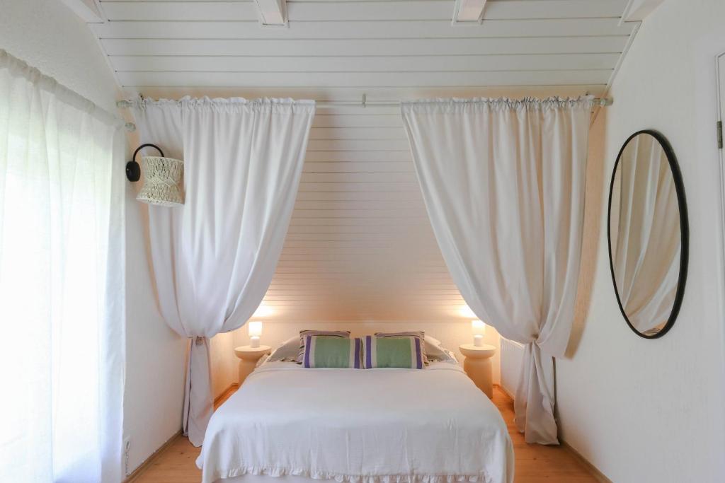 a bedroom with a bed with curtains and a mirror at Lake House Erkulis near Kuldiga in Kuldīga