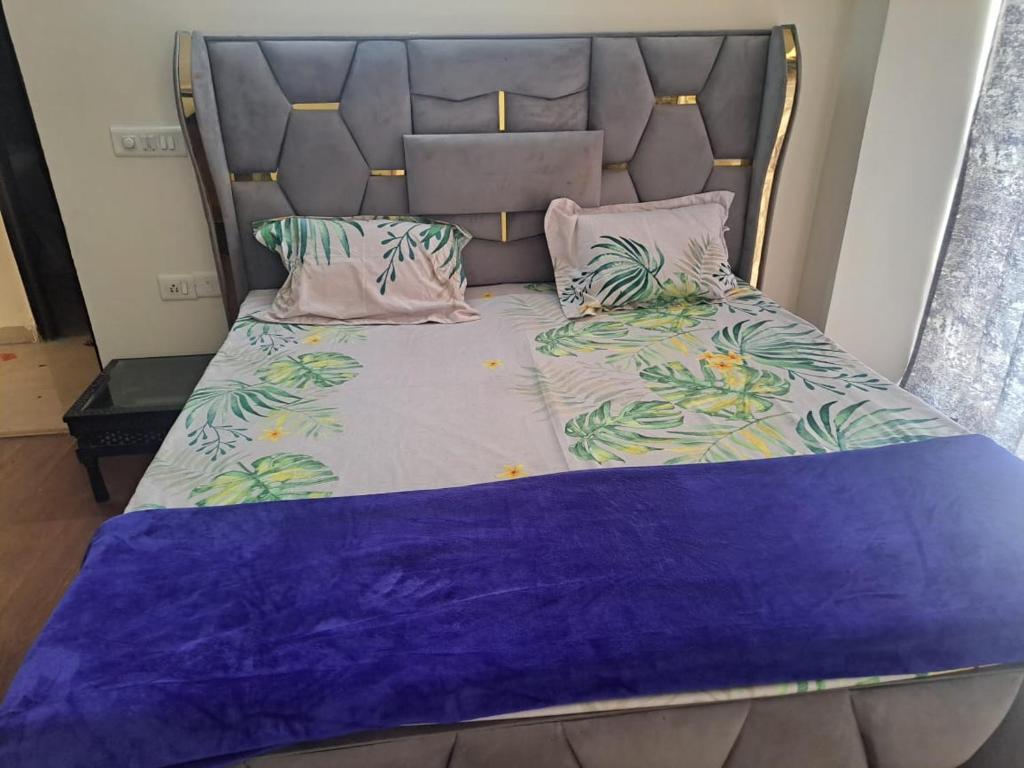 a bed with a head board with purple sheets and pillows at 2Bhk fully furnished flat. in Ghaziabad