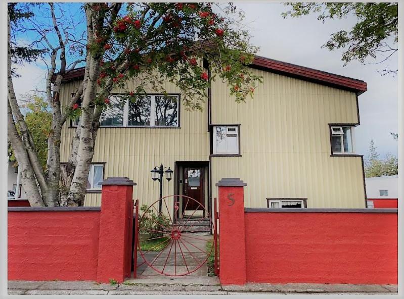 a house with a red fence in front of it at Akureyri Center Rooms in Akureyri