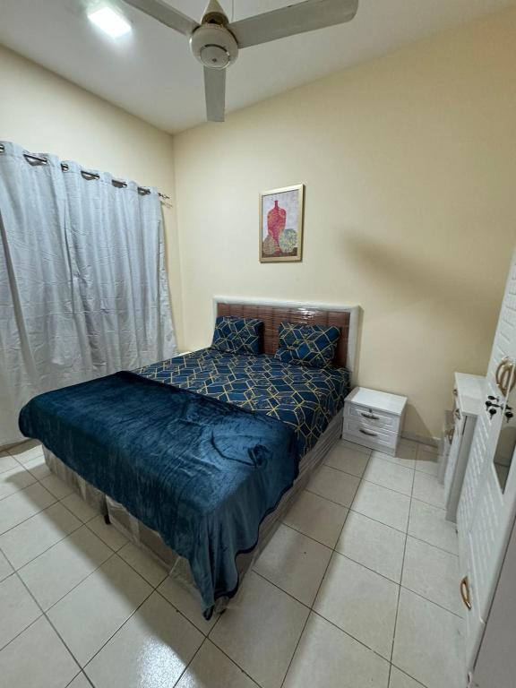 a bedroom with a bed with a blue comforter at Decent Private family Rooms with Shared washroom next to Burjuman Metro in Dubai