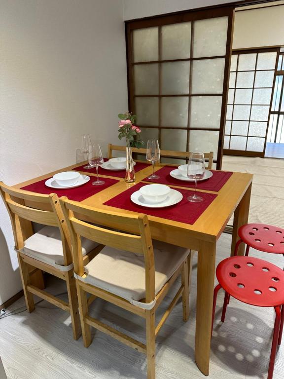 una mesa de madera con platos y copas de vino. en Guest House" Ro" takezaki, en Amanogōchō