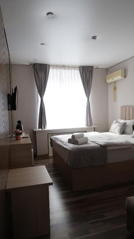 a bedroom with a bed and a large window at AG Hotel Nazarbaeva in Almaty