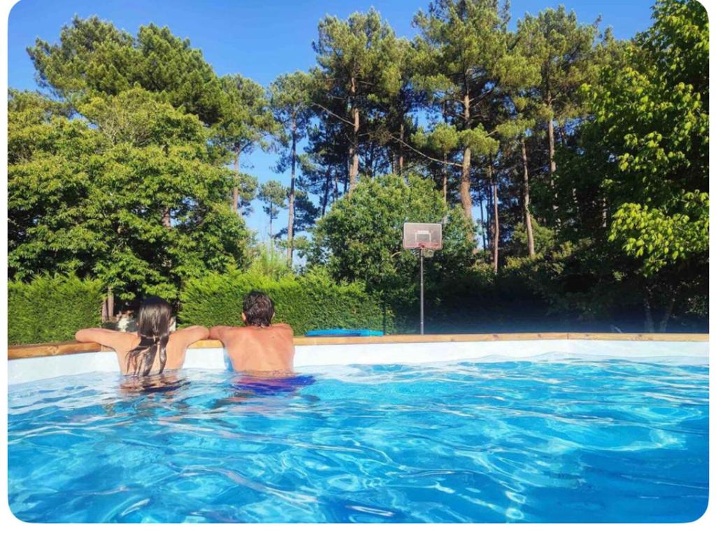 un homme et une femme jouant au basket-ball dans une piscine dans l'établissement Grande Maison Familiale entre lac et océan, à Vielle-Saint-Girons
