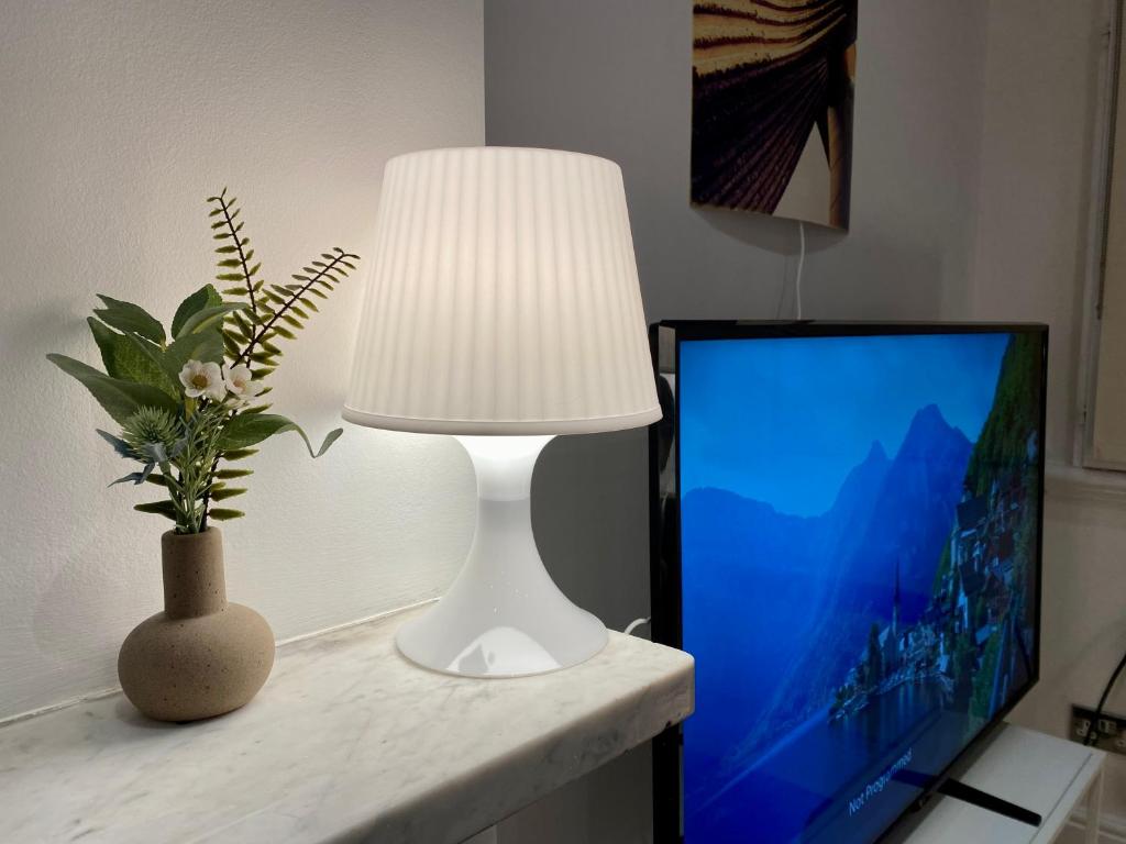 a white lamp sitting on a table next to a tv at One-bed flat Central London Payment required STRAIGHT away The host will message you after you've made a reservation in London