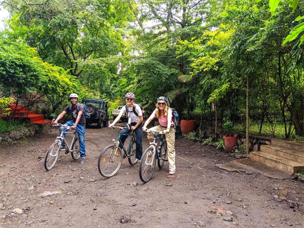 3 personnes debout avec des vélos sur un chemin de terre dans l'établissement Shamba Hostel, à Usa River