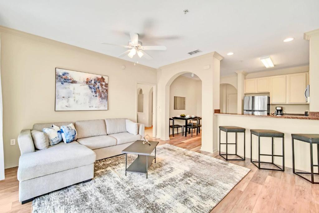 a living room with a couch and a kitchen at Bright Condo - 2BR with Pool & Hot Tub, near Disney! in Orlando