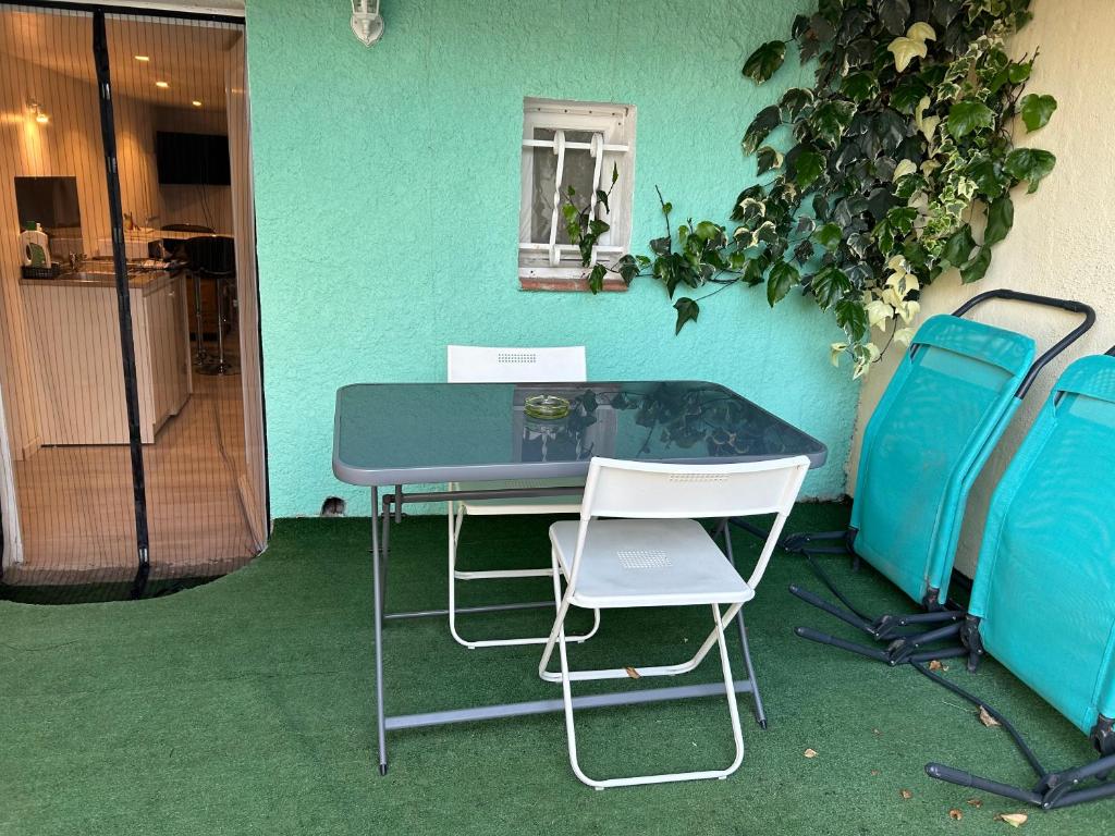 a table and two chairs in front of a green wall at Un coin en Provence in Villeneuve