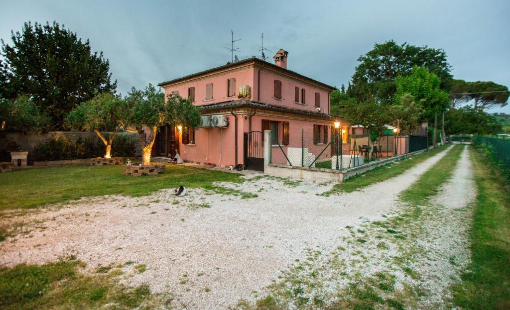 una casa rosa seduta in cima a una strada sterrata di Casa di Marco e Kaila a Tavullia