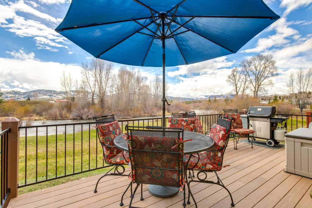 eine Terrasse mit einem Tisch, Stühlen und einem Sonnenschirm in der Unterkunft Granby Cabin Rental on Fraser River - Fish and Ski! in Granby