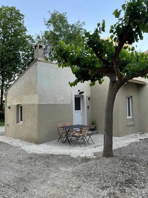 a picnic table and a tree in front of a building at MAZET en CAMPAGNE in Arles