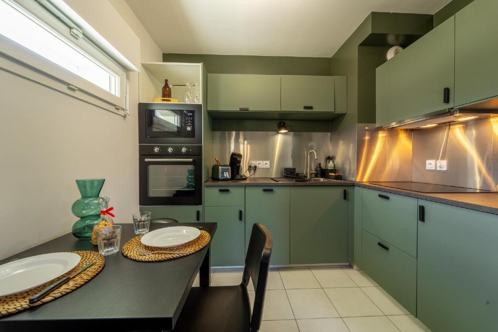 une cuisine avec des placards verts et une table avec des chaises dans l'établissement Appartement en bord de lac, à Aix-les-Bains