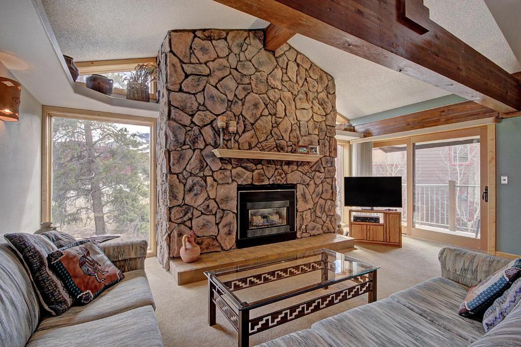 una sala de estar con una gran chimenea de piedra. en Sawmill Creek Condo 309 by Great Western Lodging en Breckenridge