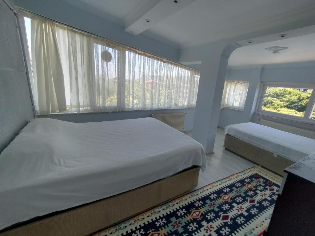 a bedroom with two beds and windows and a rug at VİLLA FERHAT TATİL EVLERİ in Sile