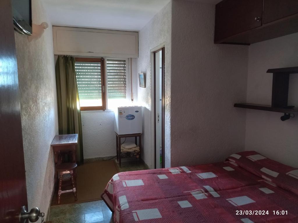 1 dormitorio con 1 cama con colcha roja y ventana en TIEN TAI TUNA en La Paloma