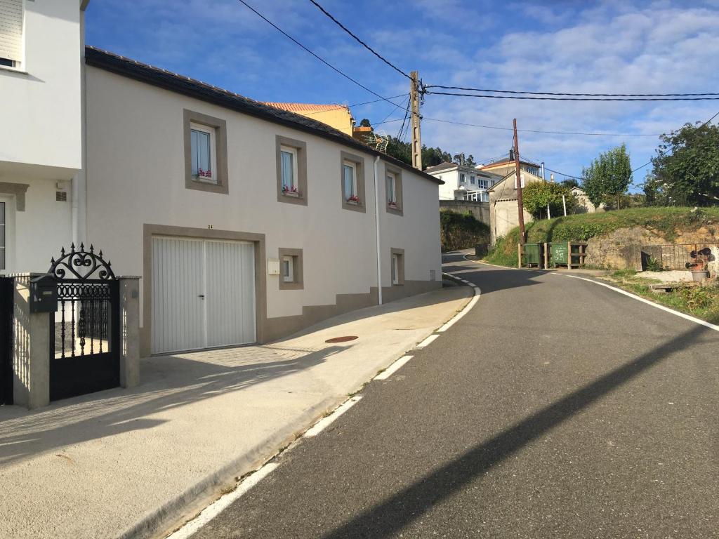 an empty street with a white house with a garage at La casa de Manuel en Ortigueira in A Coruña