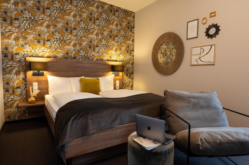 a bedroom with a bed and a laptop on a stool at V Boutique Hotel Böblingen in Böblingen
