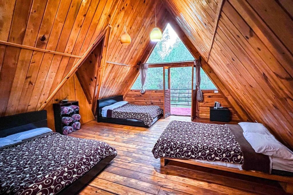 a attic room with two beds and a window at Chalet privado en el bosque con Jacuzzi de Madera Huasca Retreats in Huasca de Ocampo