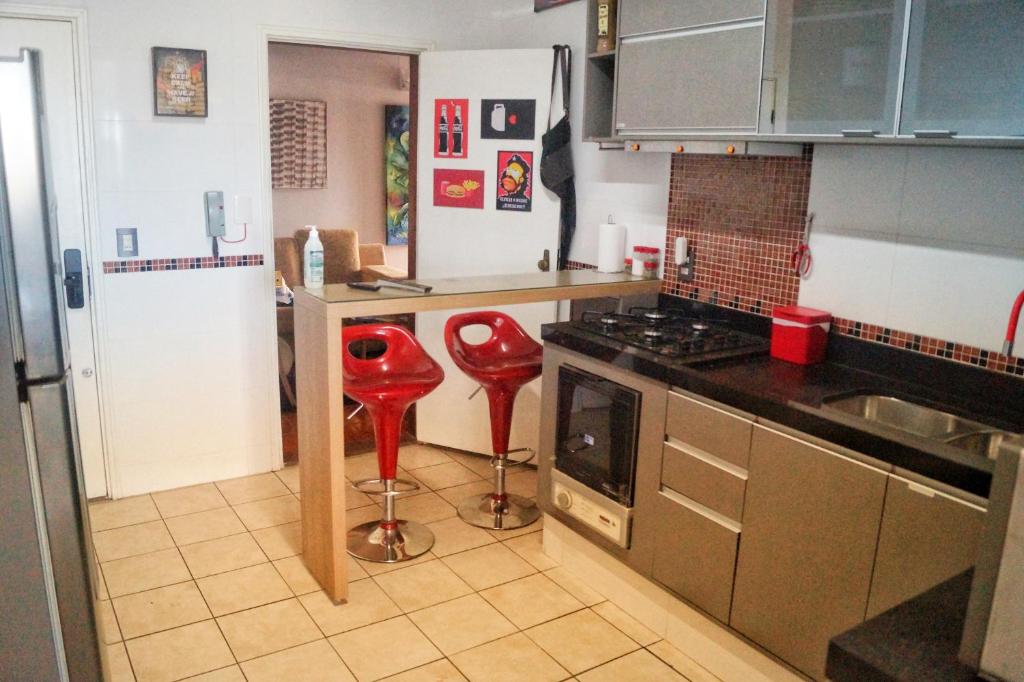 a kitchen with a stove and red stools in it at AnaLuiza Smarthome in Sao Jose do Rio Preto
