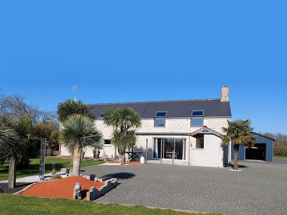 une maison avec des palmiers en face d'une allée. dans l'établissement Maison de charme, à Yvetot Bocage