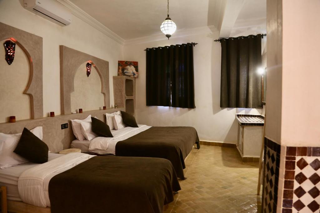 Habitación de hotel con 3 camas y espejo en Riad Desert Man en Merzouga