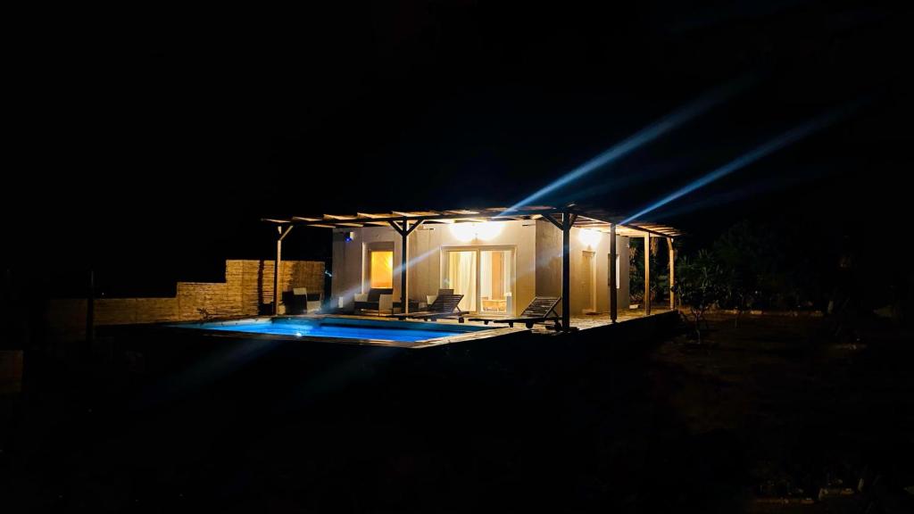 una casa iluminada por la noche con una piscina en Andromeda en Tsoútsouros