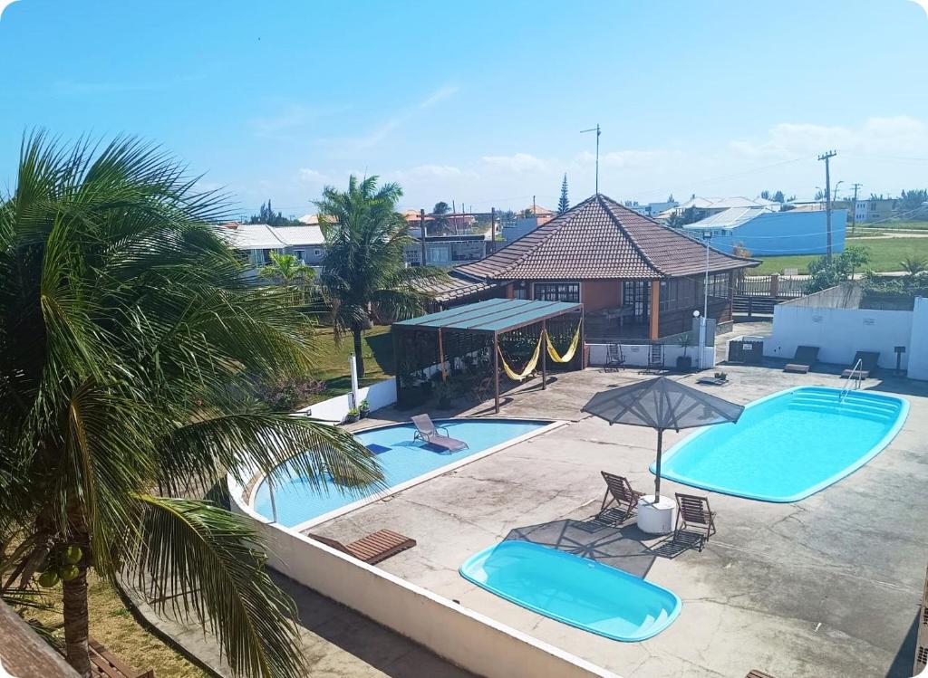 una vista panoramica su due piscine con sedie e ombrelloni di Villaggio dos Ventos ad Arraial do Cabo