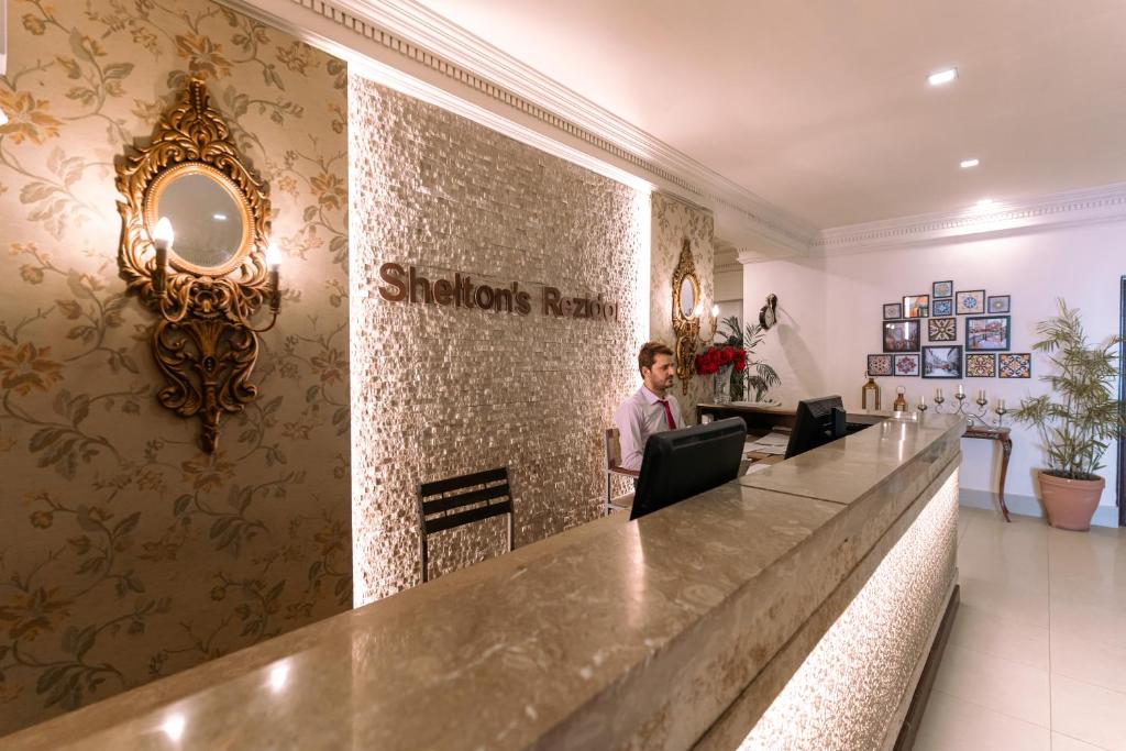 a man standing at a reception desk in a hotel lobby at Shelton Rezidor House Peshawar in Peshawar