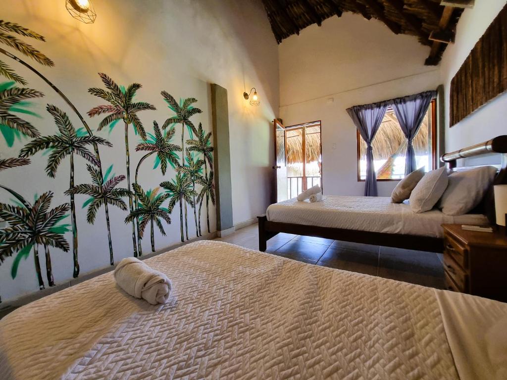 a bedroom with a bed and palm trees on the wall at Kite Eco House in Salina de Rey