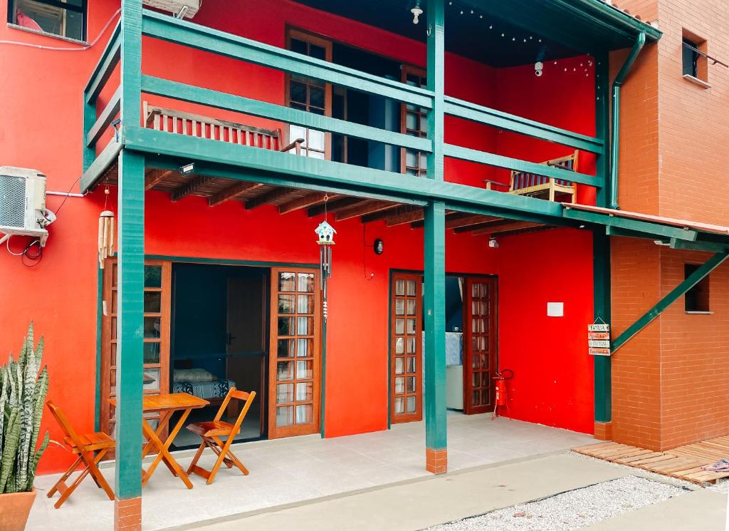 czerwony budynek z balkonem, stołem i krzesłami w obiekcie Sagui Hostel w mieście Florianópolis