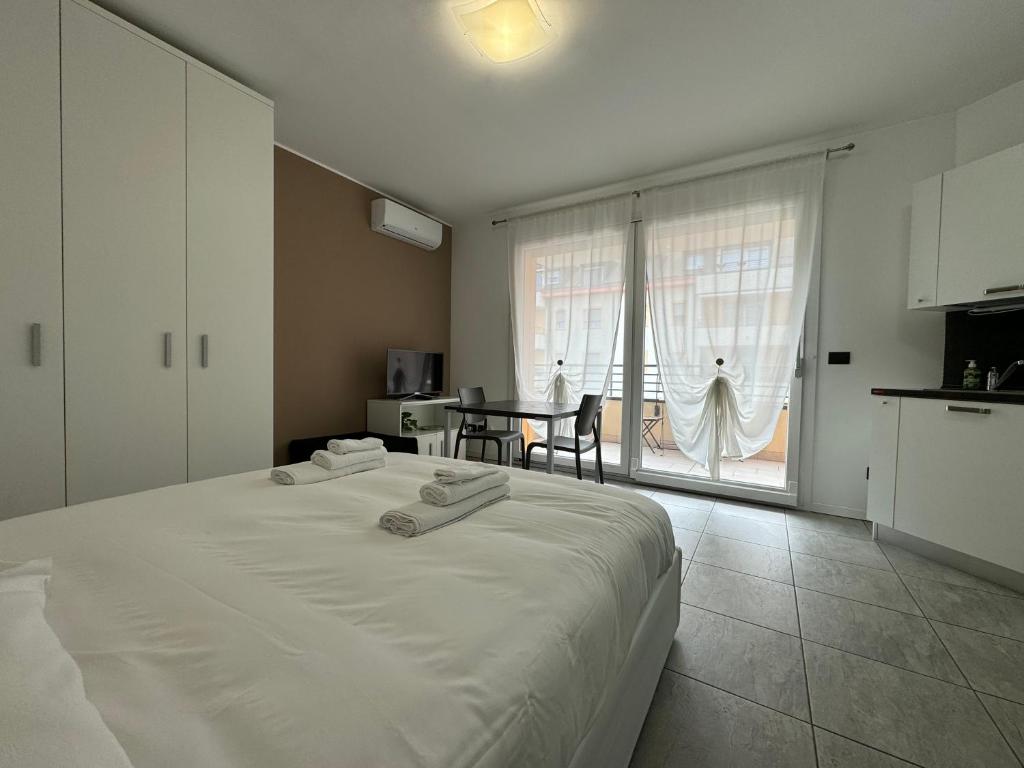 Un dormitorio con una gran cama blanca y una mesa en APPARTAMENTO FIERA MILANO - Affitti brevi Italia, en Pero